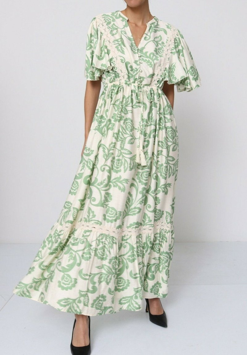 Robe maxi avec un imprimé floral vert sur fond crème, manches courtes, taille cintrée et bord en dentelle le long de l'ourlet.