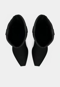 Ζευγάρι μαύρα μποτάκια αστραγάλου με μυτερές μύτες και χαμηλό τακούνι, φωτογραφημένα από ψηλά σε λευκό φόντο.