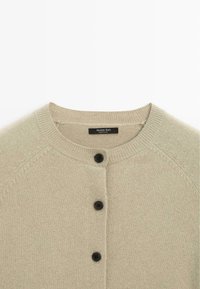 Cardigan di lana verde chiaro con collo rotondo, dotato di cinque bottoni neri sul davanti e un motivo a maglia testurizzata.