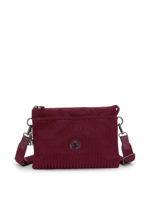 Maroon crossbody bag with textured fabric, zipper closure, and adjustable strap. Features a logo emblem on the front. Compact and rectangular shape.