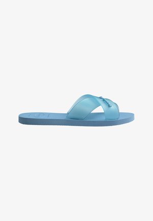 Sandale mule en caoutchouc bleu clair avec larges brides croisées et semelle texturée, vue de profil sur fond blanc.