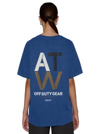 Person med opsat hår iført en blå oversized T-shirt med fed skrift "ATW OFF DUTY GEAR HALO" på ryggen.