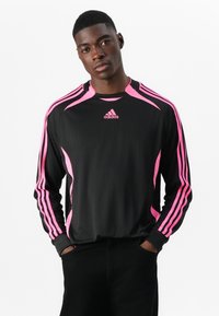 Juoda ilgomis rankovėmis sportinė marškinė su rožinėmis detalėmis ant pečių ir rankovių, su Adidas logotipu ant krūtinės. Lygi tekstūra.