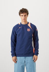Marineblå sweatshirt med lange ærmer, orange detaljer og logo på brystet. Lavet af blødt stof, har en rund halsudskæring og en afslappet pasform.