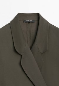 Blazer vert olive foncé avec col à revers cranté et étiquette noire "Massimo Dutti" à l'intérieur de l'encolure.
