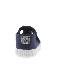 Sneaker in tela blu navy con suola in gomma bianca, dotata di un tallone a goccia e di un'etichetta cucita sul retro. Design semplice e minimalista.