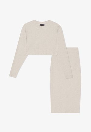 Helles beige, geripptes zweiteiliges Set mit einem kurzärmeling Oberteil und einem knielangen Rock, beide aus strukturiertem Strickstoff gefertigt.