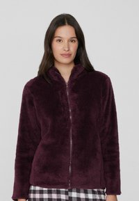 Chaqueta de felpa con cremallera en burdeos profundo, con una textura suave y cuello alzado. Presenta mangas largas y un ajuste relajado.