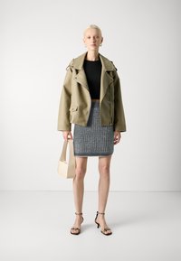 Olīvzaļš mākslīgās ādas motokrekls, melns īss tops, strukturēts pelēks adījums svārki, krēmkrāsas rokassoma, melnas sandales ar siksniņām. Vienkārša un moderna silueta.