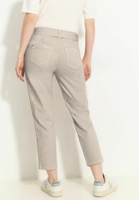 Pantalon court gris clair avec une taille élastique, deux poches arrière et une coupe décontractée, associé à des sneakers blanches avec un accent bleu.
