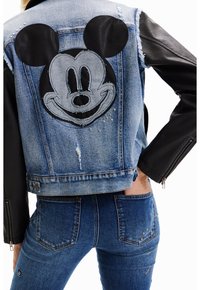 Jeansjacka med svarta lädersärmar, med ett stort broderat Mickey Mouse-ansikte på ryggen och metalliska dekorationer.