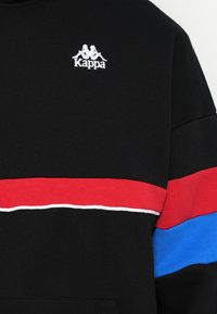 Felpa nera con logo Kappa, dettagli bianchi e strisce orizzontali rosse e blu sul petto. Realizzata in tessuto testurizzato.