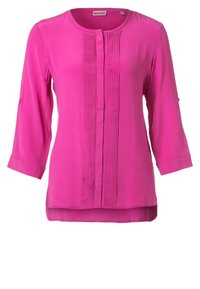 Chemisier rose à manches longues avec un col rond, fermeture à boutons sur le devant et des détails plissés. Tissu léger et doux avec un bas légèrement transparent.