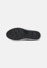 Suela de zapato de goma negra con un patrón de agarre texturizado, que presenta un diseño de banda de rodadura en forma de diamante y un borde blanco en contraste.