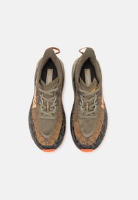 Olive green athletic shoes with a textured brown upper, black accents, and orange details. Features laces and a cushioned sole design.