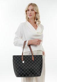 Zwarte tote bag met een diamantenpatroon, bruine leren handvatten en een metalen accent. Soepele textuur met een gestructureerde vorm.