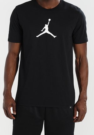 Svart bomullströja med en stor vit Jumpman-logga. Korta ärmar, rundad halsringning och lös passform. Matchas med svarta shorts.