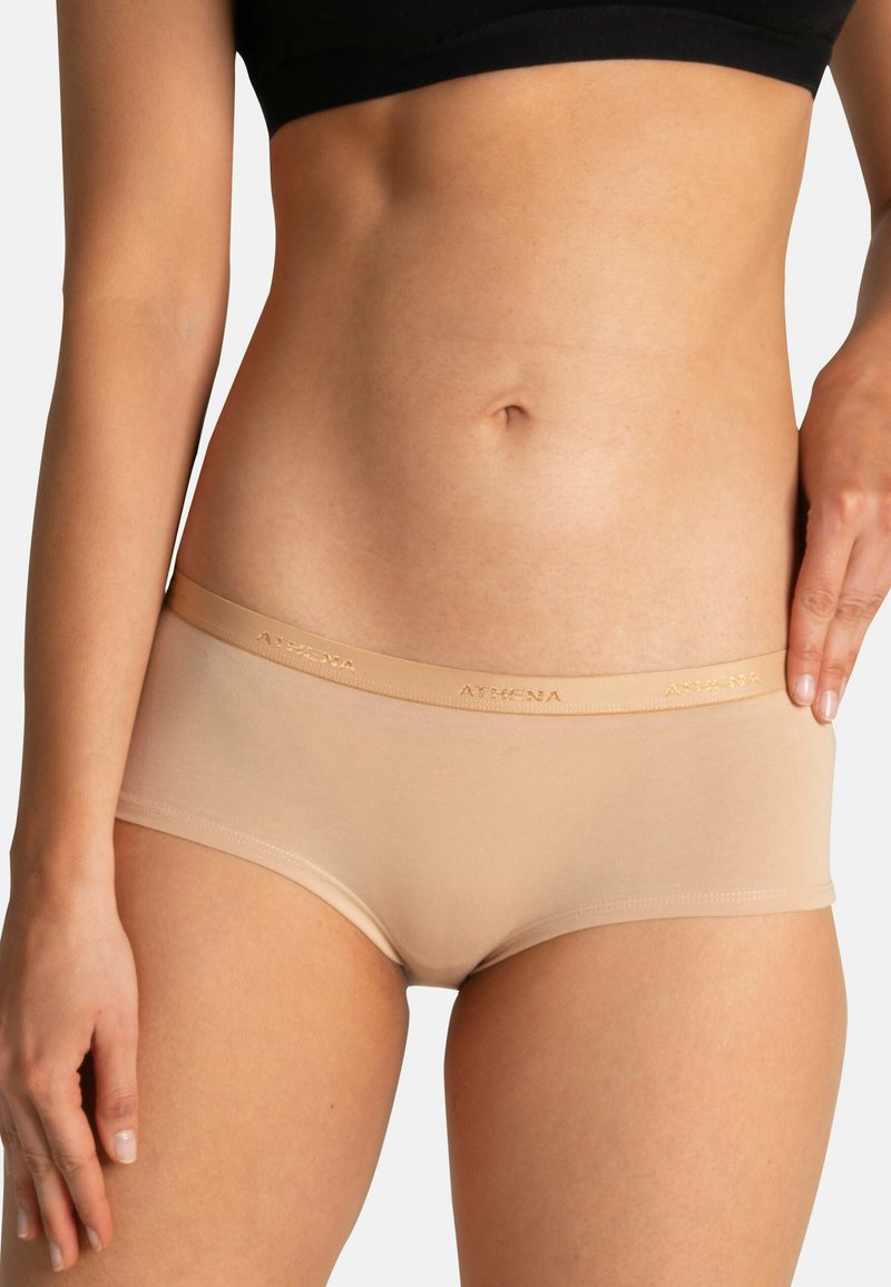 Shorts garçon en coton beige avec une taille élastique douce arborant un logo de marque en relief. Texture lisse, coupe mi-haute et style ajusté.