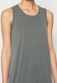 Mouwloze, geribde tanktop in een gedempt groene kleur. Het materiaal lijkt zacht en heeft een relaxte pasvorm met subtiele textuur. Ronde halslijn.