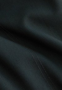 Sort ribbet stof med en subtil glans, hvor synlige sømmen skaber tekstur og dybde. Blødt, strækbart materiale.