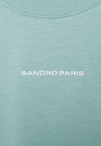 Felpa corta mint verde con maniche corte, caratterizzata dalla scritta "SANDRO PARIS" ricamata in bianco. Tessuto morbido e leggero con una superficie liscia.