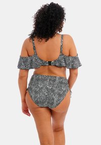 Bikini noir et blanc à pois avec des manches froncées et un bas taille haute, featuring des liens sur le côté réglables pour un ajustement sécurisé.