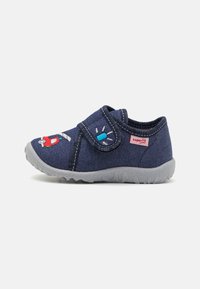 Modra tekstilna pantofla z velcro trakom, sivo gumijasto dno in vezenimi risanimi detajli, vključno z rdečim vozilom in lučjo.
