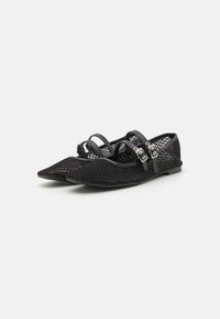 Ballerines noires avec un design en maille, bout pointu et deux accents de sangle avec du matériel en métal argenté. La texture est tissée et légère.
