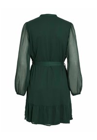 Rochie verde închis cu mâneci lungi din material transparent, talie evidențiată printr-un cordon și un tiv ondulat. Fabricată dintr-un material ușor, are un guler rotund.