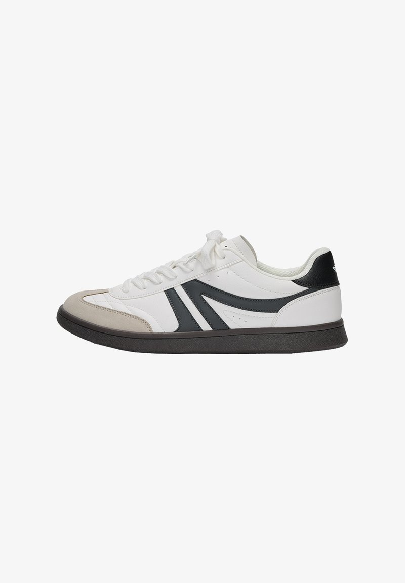 Weißer Sneaker mit einem glatten Lederobermaterial, grauem Wildleder-Zehenschutz, dunkelgrauen Akzenten und einer schwarzen Ferse, auf einer schwarzen Gummisohle.