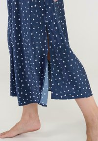 Vestido azul marino con patrones de estrellas blancas, de longitud hasta la rodilla y con aberturas laterales, hecho de una tela suave, destacando un corte holgado y un estilo casual.