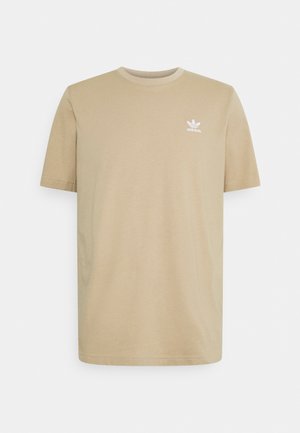 T-shirt beige à manches courtes Adidas avec col rond et petit logo trèfle blanc sur le côté gauche de la poitrine.