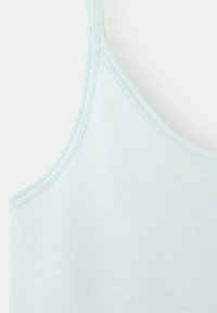 Gros plan sur un haut sans manches bleu clair montrant les détails de l'encolure et des bretelles cousues sur un fond blanc.