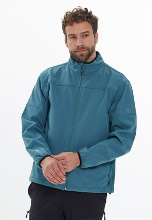 Veste softshell teal avec un col montant, fermeture éclair frontale, poignets élastiques et poches latérales ; texture lisse avec des coutures discrètes.