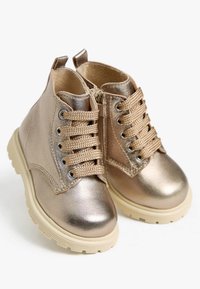 Metallic gold Stiefeletten mit strukturiertem Finish, vorderer Schnürung und seitlichem Reißverschluss. Klobige Sohle in Cremefarbe. Mit Ösen und gestickten Details.