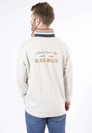 Chemise à longues manches gris clair avec un col à pois navy et des accents rayés. Le dos présente une broderie dorée avec les mots "Maison Casual Chic BLACK WELLIS."
