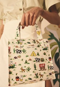 Lille, cremefarvet tote bag med et legende dyre- og naturprint, holdbare håndtag og en blank, tekstureret finish.