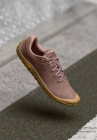 Baskets rose clair avec une semelle en caoutchouc texturé, des lacets plats et un dessus respirant. Présente un logo sur le côté et un motif de semelle flexible.