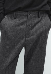 Pantaloni grigi con un motivo a trama fine, dotati di chiusura con bottone e tasche laterali. Il tessuto appare morbido e leggermente spazzolato.