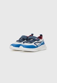 Zapatillas deportivas azul y blancas con parte superior de malla, correa de velcro, suela texturizada y acentos en marrón. Presenta texto del logo en el lateral.
