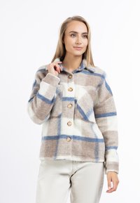 Fleece overhemdjack met een bruin, blauw en crèmekleurig ruitpatroon; voorzien van een kraag, twee borstzakken en houten knopen.