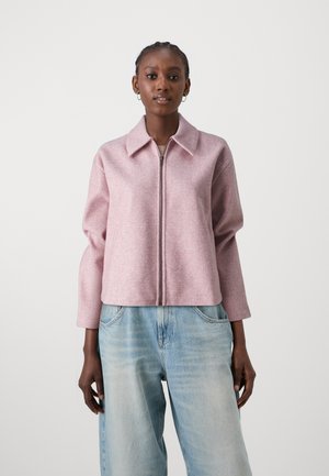 Pink wool-blend cropped jacket with a large collar, front zipper, and long sleeves paired with light blue high-waisted jeans.