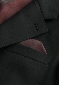 Black blazer with a textured finish, featuring a red patterned pocket square visible in the breast pocket. Clean lapel detail.