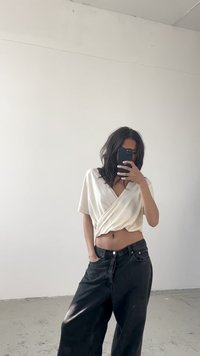Cremefarvet wrap-top med korte ærmer, parret med løse sorte denimbukser. Glat tekstur, afslappet pasform og en midriff-baring design.