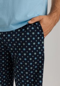 Light blue t-shirt paired with navy pajama pants featuring a small floral pattern in blue and gold, with pockets and soft fabric texture.