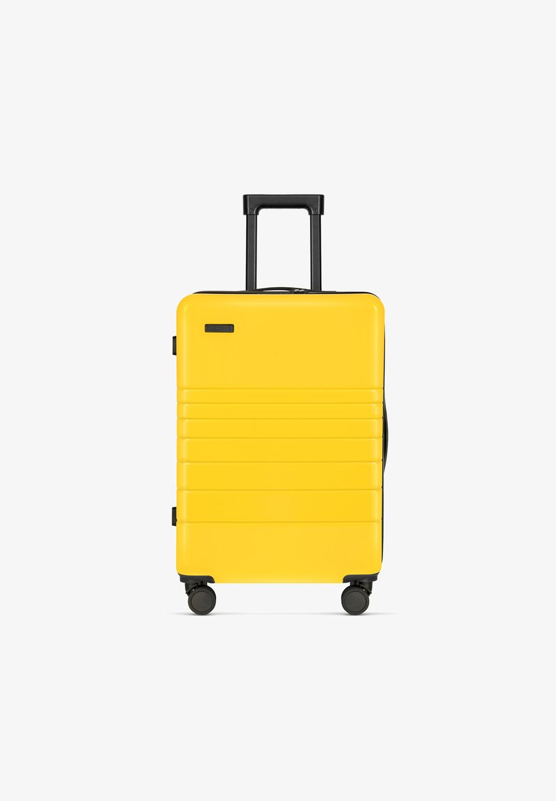Gelbes Hartschalenkofferset mit schwarzen Akzenten, teleskopischem Griff, vier Rädern und strukturierten Seitenpaneelen für Stabilität.