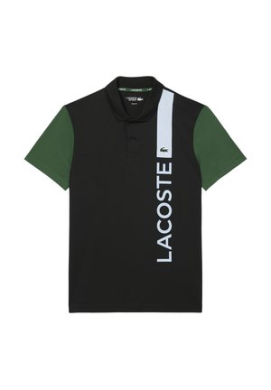 Camisa polo de manga corta negra con mangas verdes, raya vertical blanca con el texto "LACOSTE", pequeño logo de cocodrilo en el pecho.