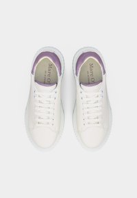 Ζευγάρι λευκά αθλητικά παπούτσια με μοβ λεπτομέρειες, λευκά κορδόνια και παχιές σόλες, που φαίνονται από πάνω σε απλό φόντο.