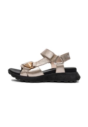 Sandał otwarty na palce w metalicznym złotym kolorze z czarną grubą podeszwą, regulowanymi paskami na rzep i ozdobną złotą klamrą na przednim pasku.