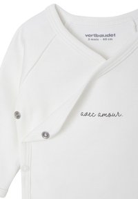 Weißes Baumwollbaby-Body mit Druckknöpfen und Wickeldesign, versehen mit grauem Text, der "avec amour" liest. Weiche, glatte Textur, geeignet für Säuglinge.